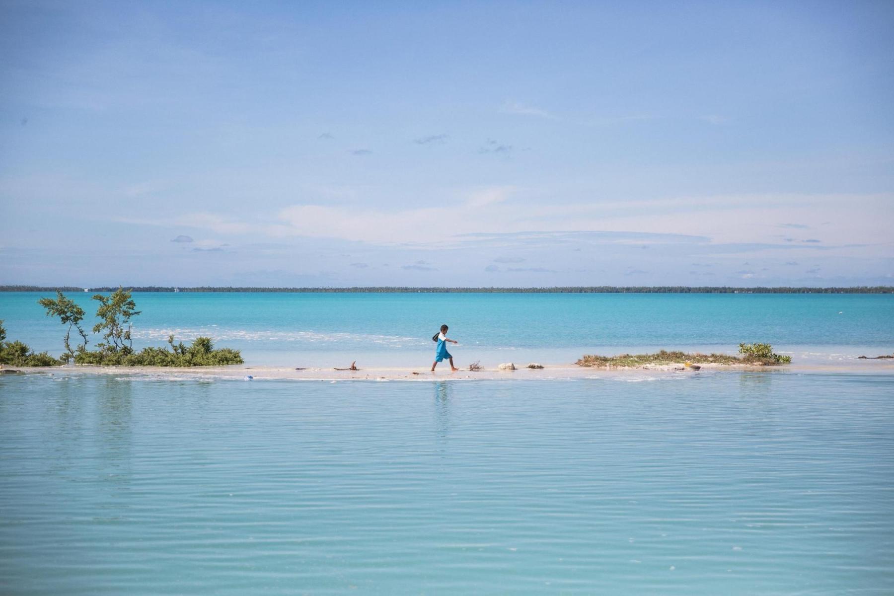 A child walking along a narrow piece of land between two bodies of water